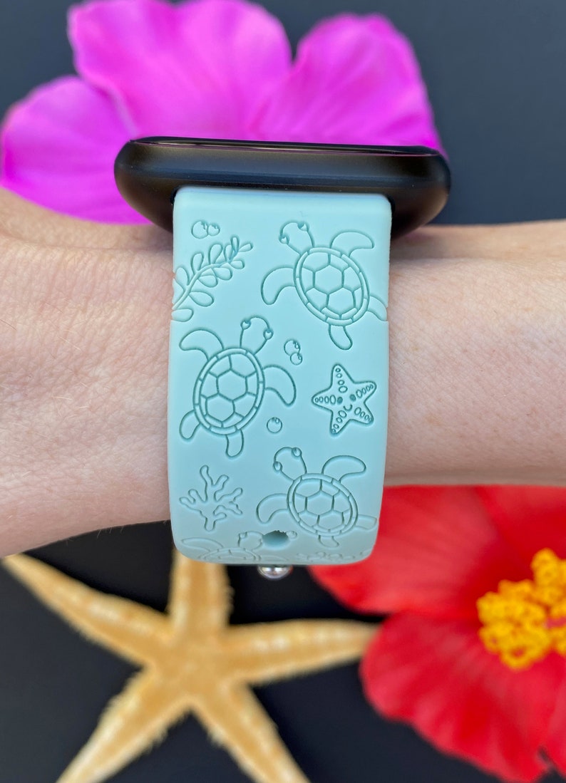 May include: A light blue silicone Apple Watch band with a sea turtle and starfish design.