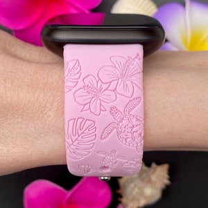 May include: Pink silicone watch strap with a tropical floral and sea turtle design. The strap is shown on a wrist.