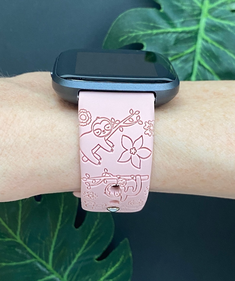 May include: A pink silicone watch band with a sloth design. The band has a white outline and is compatible with smartwatches.