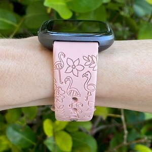 May include: A pink silicone watch band with a flamingo and floral pattern. The band is designed for a smart watch.