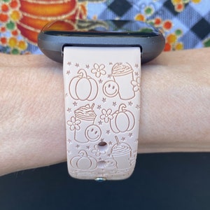 May include: A pink silicone watch band with a pattern of pumpkins, coffee cups, and stars. The band is designed for a smartwatch.