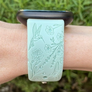 May include: A light green silicone watch strap with a floral and hummingbird design.