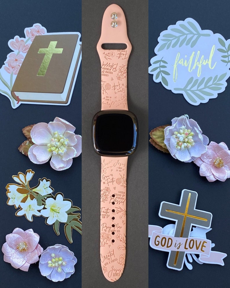 May include: A pink Apple Watch band with a floral design and inspirational quotes including "Grow in Faith", "Jesus Loves", "Faith", "Pray More", and "Blessed".