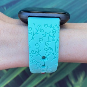May include: A turquoise blue watch band with a floral pattern. The band is made of silicone and has a textured surface.