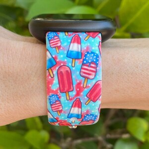 May include: A blue and red patterned watch band with a design of ice cream pops with American flag colors. The band is made of silicone and is compatible with smartwatches.