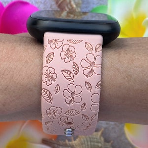 May include: A pink silicone watch strap with a floral pattern. The strap has a white background with pink flowers and leaves.