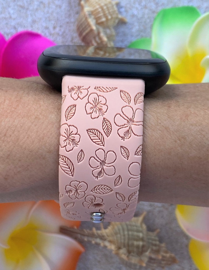 May include: A pink silicone watch strap with a floral pattern. The strap has a white background with pink flowers and leaves.