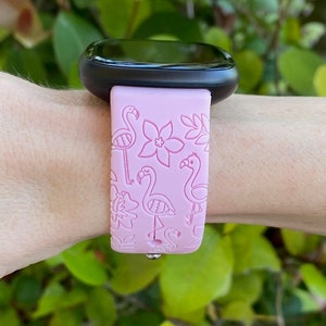 May include: A pink silicone watch band with a flamingo and floral design. The band is compatible with smartwatches.