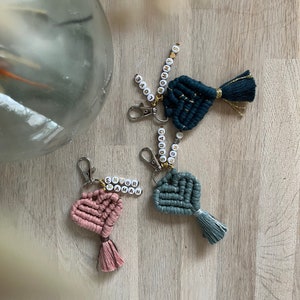 Peut inclure: Trois porte-clés en forme de cœur avec des glands. Chaque porte-clés a une chaîne perlée avec des lettres dorées qui épellent "Mommy's", "Enor Maman" et "Dad".