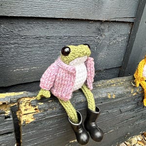 Grenouille de poche articulée tricotée à la main : ami amphibien fait main. Grenouille amigurumi. amoureux des grenouilles. Poupée grenouille avec veste et bottes rose-violet mouchetée