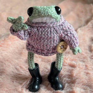 Grenouille tricotée à la main portant un pull rose moucheté pourpre tricoté à la main. Grenouille de poche posable. Cadeau d'anniversaire. Amoureux des grenouilles. Animal de compagnie tricoté.