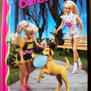 Puede incluir: Una portada de libro con una muñeca Barbie de pelo rubio que lleva una camisa amarilla y un mono, sujetando una correa atada a un cachorro golden retriever. El cachorro sostiene un frisbee azul. El texto de la portada dice "Barbie La mejor amiga".