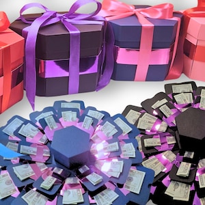 May include: A collection of colorful explosion gift boxes and money flower arrangements. The boxes are in various colors, including red, pink, purple, and black, with matching ribbons. The money flowers are in red, blue, and pink, with dollar bills visible.