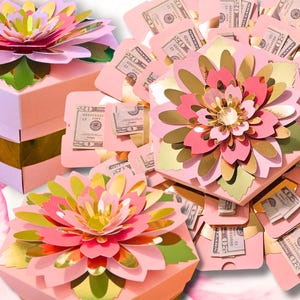 May include: Pink, gold, and green paper flower gift boxes. The boxes are hexagonal and topped with layered paper flowers. The text "MONEY NOT INCLUDED" is at the bottom. Some boxes are open, revealing money.