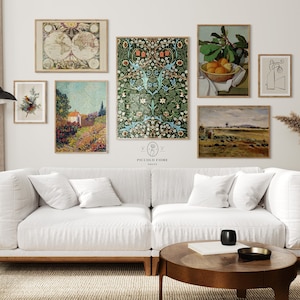 May include: A collection of framed art prints displayed above a white sofa. The art includes a world map, floral patterns, still life with oranges, and abstract line drawings. The prints are in various sizes and styles, creating a gallery wall aesthetic.