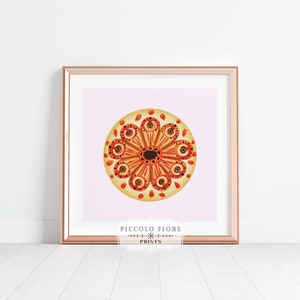 May include: A framed print of a colorful mandala with a pink background. The mandala is a circular design with orange, yellow, and red colors. The text "PICCOLO FIORE PRINTS" is at the bottom of the print.