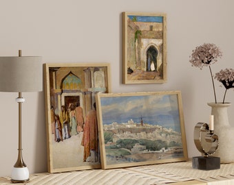 Può includere: Tre dipinti incorniciati che raffigurano scene di una città del Nord Africa. I dipinti sono in una cornice di legno chiaro e sono appesi a una parete di colore beige chiaro. I dipinti sono di dimensioni diverse e sono disposti in uno schema sfalsato. I dipinti sono tutti in stile realistico e raffigurano scene di persone, edifici e paesaggi.