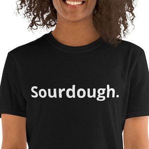May include: A black short-sleeved t-shirt with the word "Sourdough." printed in white on the front.