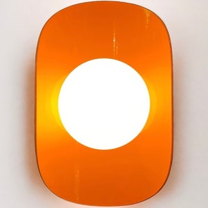 May include: Orange wall sconce with a round white light in the center.