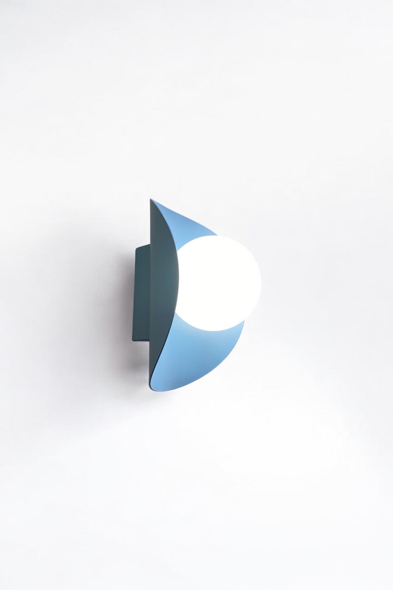 May include: A blue wall sconce with a white globe light bulb. The sconce is shaped like a crescent moon.