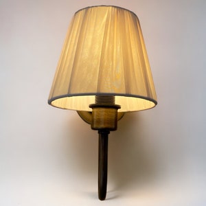 May include: A wall-mounted lamp with a cream-coloured fabric shade and a dark brown metal base.