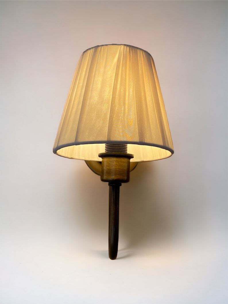 May include: A wall-mounted lamp with a cream-coloured fabric shade and a dark brown metal base.