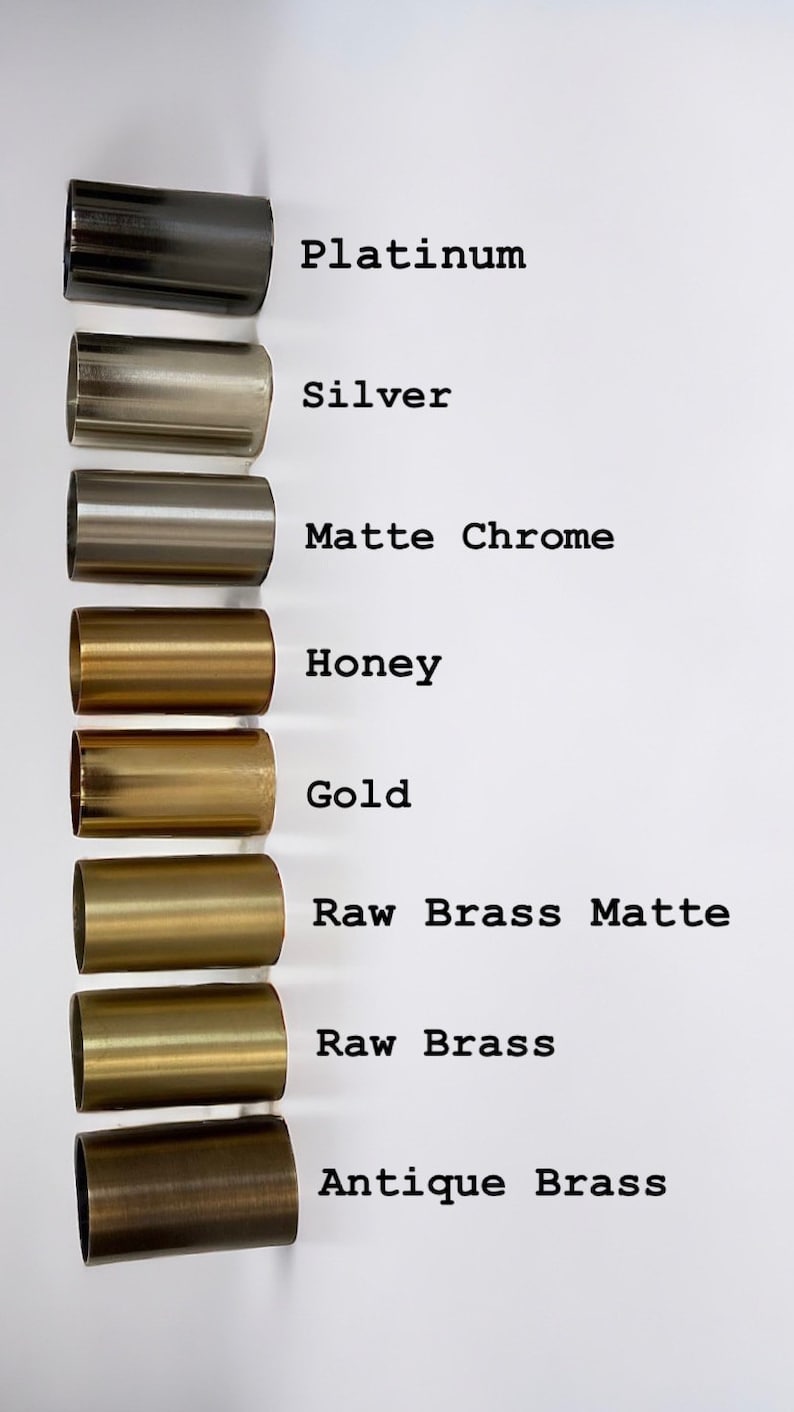 May include: A close-up of eight metal cylinders in different finishes, from left to right: platinum, silver, matte chrome, honey, gold, raw brass matte, raw brass, and antique brass.