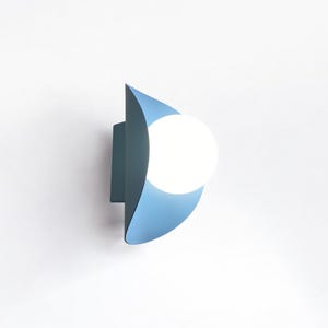 May include: A blue wall sconce with a white globe light bulb. The sconce is shaped like a crescent moon.