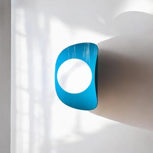 May include: A blue and white wall sculpture with a circular opening in the center. The sculpture is mounted on a white wall.