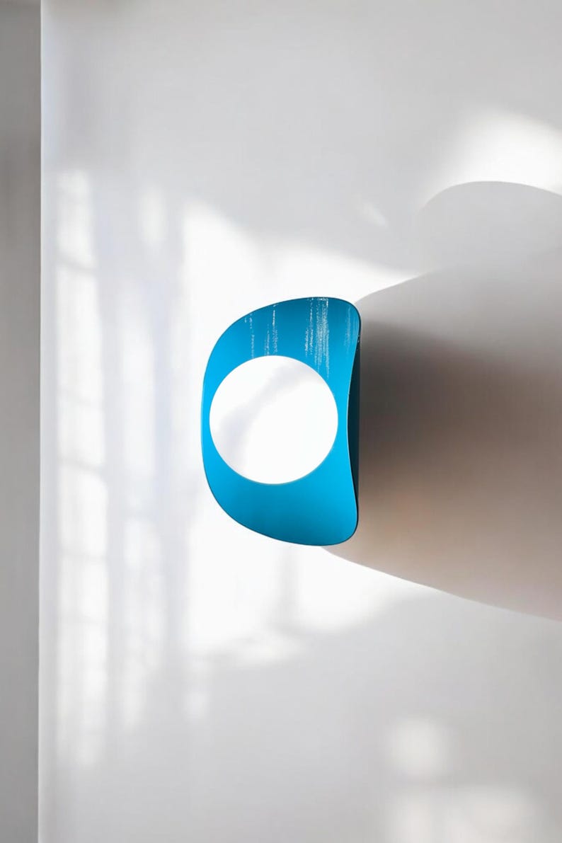 May include: A blue and white wall sculpture with a circular opening in the center. The sculpture is mounted on a white wall.
