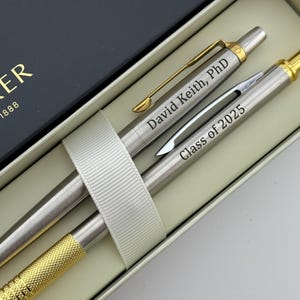 May include: A silver Parker pen set in a black box. The pen is engraved with the text "David Keith, PhD" and "Class of 2025".