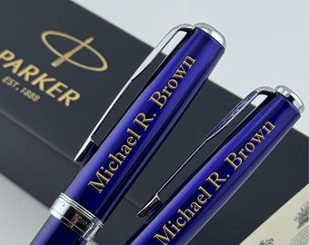 May include: Two deep blue Parker Sonnet fountain pens with silver-toned clips and trim. Each pen is engraved with the name Michael R. Brown in gold lettering. The pens are positioned in front of a black Parker brand presentation box.