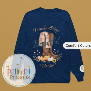 May include: Navy blue long-sleeve shirt with a fall-themed graphic. The graphic includes brown boots, a scarf, pumpkins, and the text "He makes all things Beautiful in His time!" The shirt also has the text "Comfort Colors".