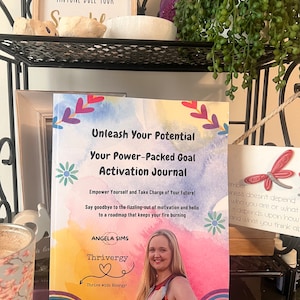 Puede incluir: Un libro colorido titulado "Desata tu potencial: Tu diario de activación de objetivos con gran poder" de Angela Sims. La portada del libro presenta a una mujer sonriendo, un arcoíris y las palabras "Thrivergy: ¡Vive con energía!"