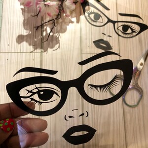 May include: A black and white silhouette of a woman's face with glasses and a closed eye. The woman is wearing thick-framed glasses with a cat-eye shape. The woman's lips are closed and her nose is small.