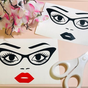 May include: Two black and white printable sticker designs of a woman's face with bold eyebrows, eyelashes, and glasses. The first design has a full face with a red lip. The second design is a close-up of the eyes and glasses.