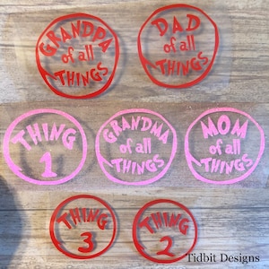 May include: Six round vinyl stickers with red and pink borders. The stickers feature the text "Grandpa of all things", "Dad of all things", "Grandma of all things", "Mom of all things", "Thing 1", and "Thing 3".