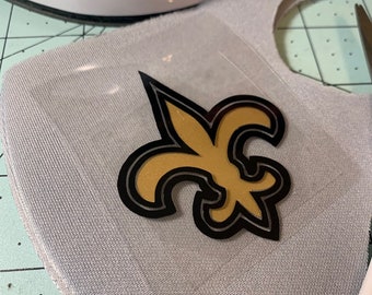 May include: A gray fabric face mask with a gold and black fleur-de-lis iron-on patch.
