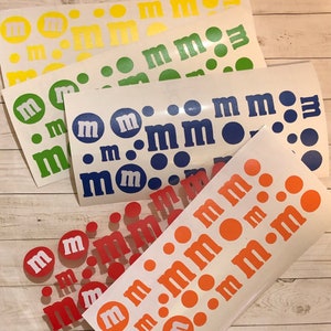 May include: Four sheets of white vinyl with different colored M&M's printed on them. The colors are yellow, green, blue, and orange.