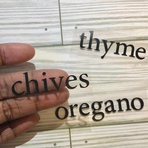 May include: Three clear labels with black text, reading "thyme", "chives", and "oregano".