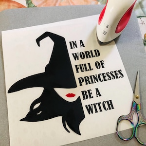 May include: A black and white silhouette of a witch with a pointed hat and red lips. The text "In a world full of princesses be a witch" is printed in black on a white background.
