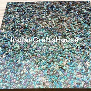 Könnte beinhalten: Eine Nahaufnahme einer Fliese aus irisierendem blauem und grünem Mosaik. Die Fliesen sind aus Perlmutt gefertigt und haben eine schimmernde, reflektierende Oberfläche. Die Fliesen sind in einem zufälligen Muster angeordnet und eignen sich perfekt, um jedem Einrichtungsprojekt einen Hauch von Eleganz zu verleihen.