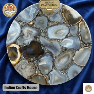 May include: A circular serving board crafted from polished agate stone. It showcases a mosaic of grey, white, and brown agate slices, forming a distinctive pattern. The text "Indian Crafts House" is visible on the board.