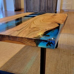 May include: A wooden table top with a blue and green epoxy resin inlay. The table has a black metal base.