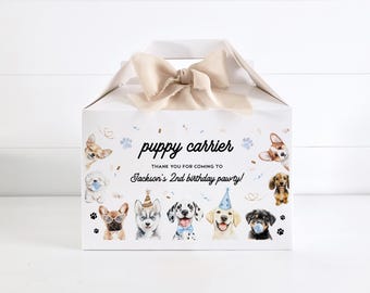 Puede incluir: Caja de regalo blanca con una cinta marrón y un diseño de transportador de cachorros azul y blanco. La caja tiene el texto "puppy carrier" y "Thank you for coming to Jackson's 2nd birthday pawty!" impreso en ella.