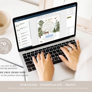 May include: A laptop computer with a screen displaying a baby shower invitation design. The invitation features a woodland theme with a deer, trees, and the text "Oh Boy!" in gold lettering. The design is being edited using the Corjl online editing platform.