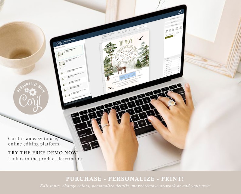 May include: A laptop computer with a screen displaying a baby shower invitation design. The invitation features a woodland theme with a deer, trees, and the text "Oh Boy!" in gold lettering. The design is being edited using the Corjl online editing platform.