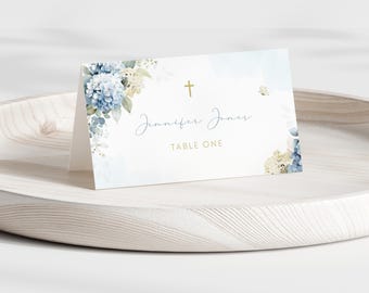 May include: Blue and white floral wedding table card with a gold cross and the text "Jennifer Jones Table One".