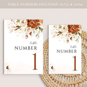 May include: Two white table number cards with a floral design in shades of brown, white, and green. The text "table number 1" is printed in brown on each card. The cards are 5x7 inches and 4x6 inches.