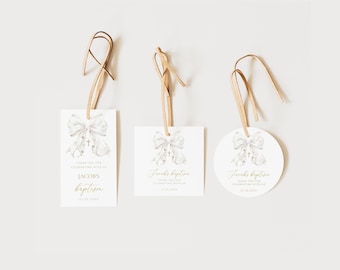 May include: Three white favor tags with gold lettering and a watercolor illustration of a white bow with a gold cross. The text on the tags reads "Thank you for celebrating with us at Jacob's Baptism".